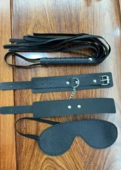Couples BDSM bondage set with mask, feather tickler, handcuffs, and ankle restraints on wooden surface