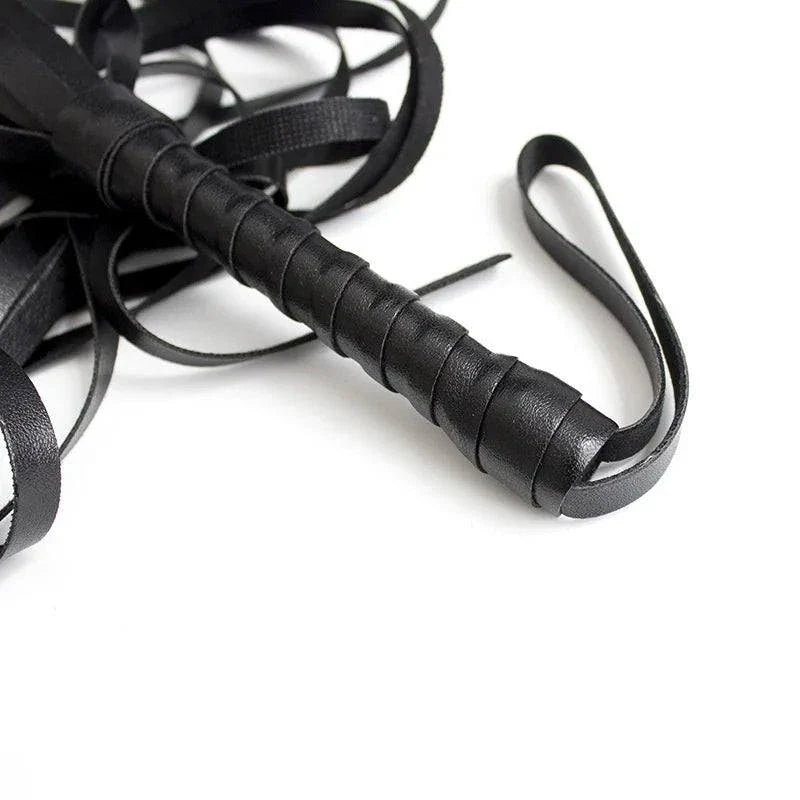 Close-up of black leather flogger whip for sensory bondage play and BDSM impact sensation.