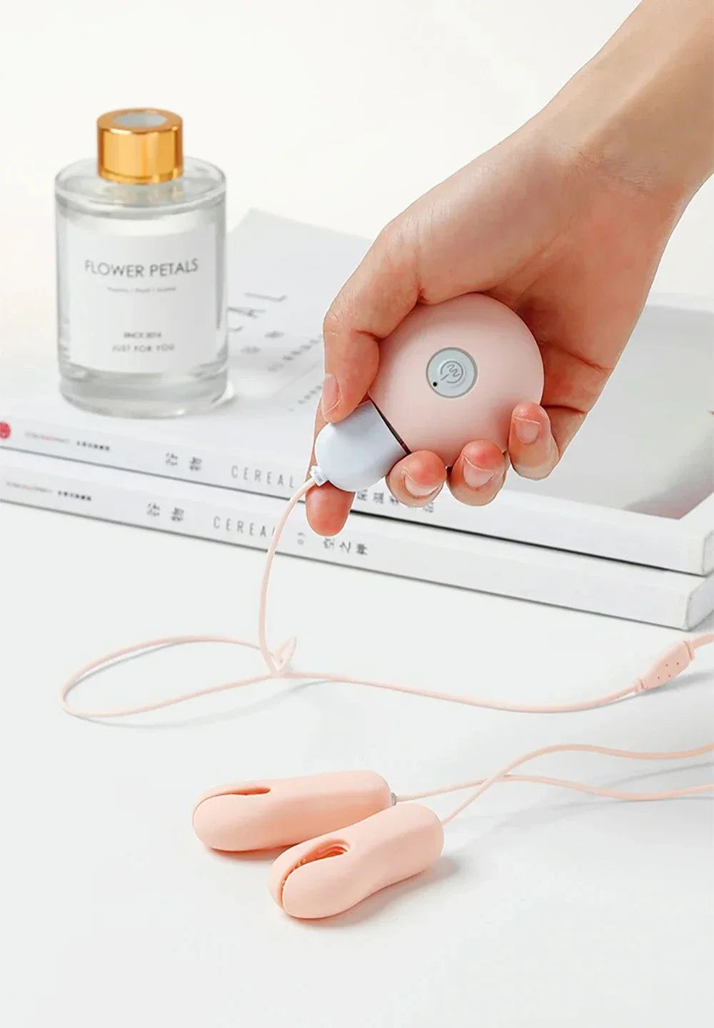Enhancer nipple stimulator breast massage clamp vibrator for women in hand with lotion bottle and books background