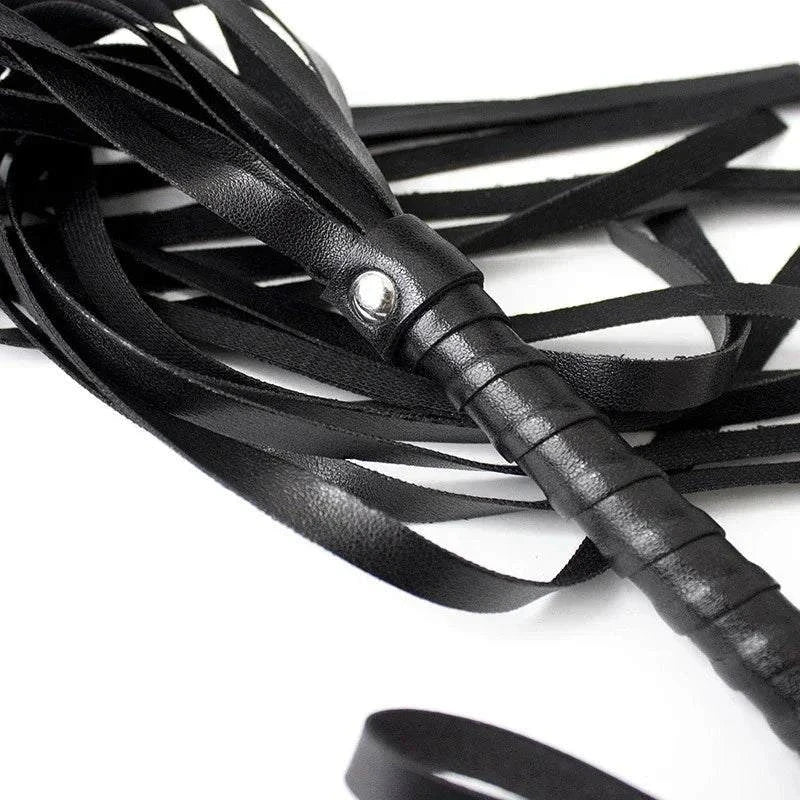 Close-up of black faux leather whip with multiple flexible strips and wrapped handle for BDSM impact play