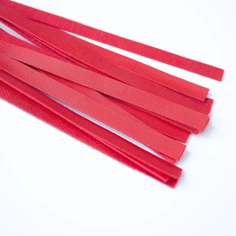 Close-up of red leather flogger strips for sensory BDSM play and impact.