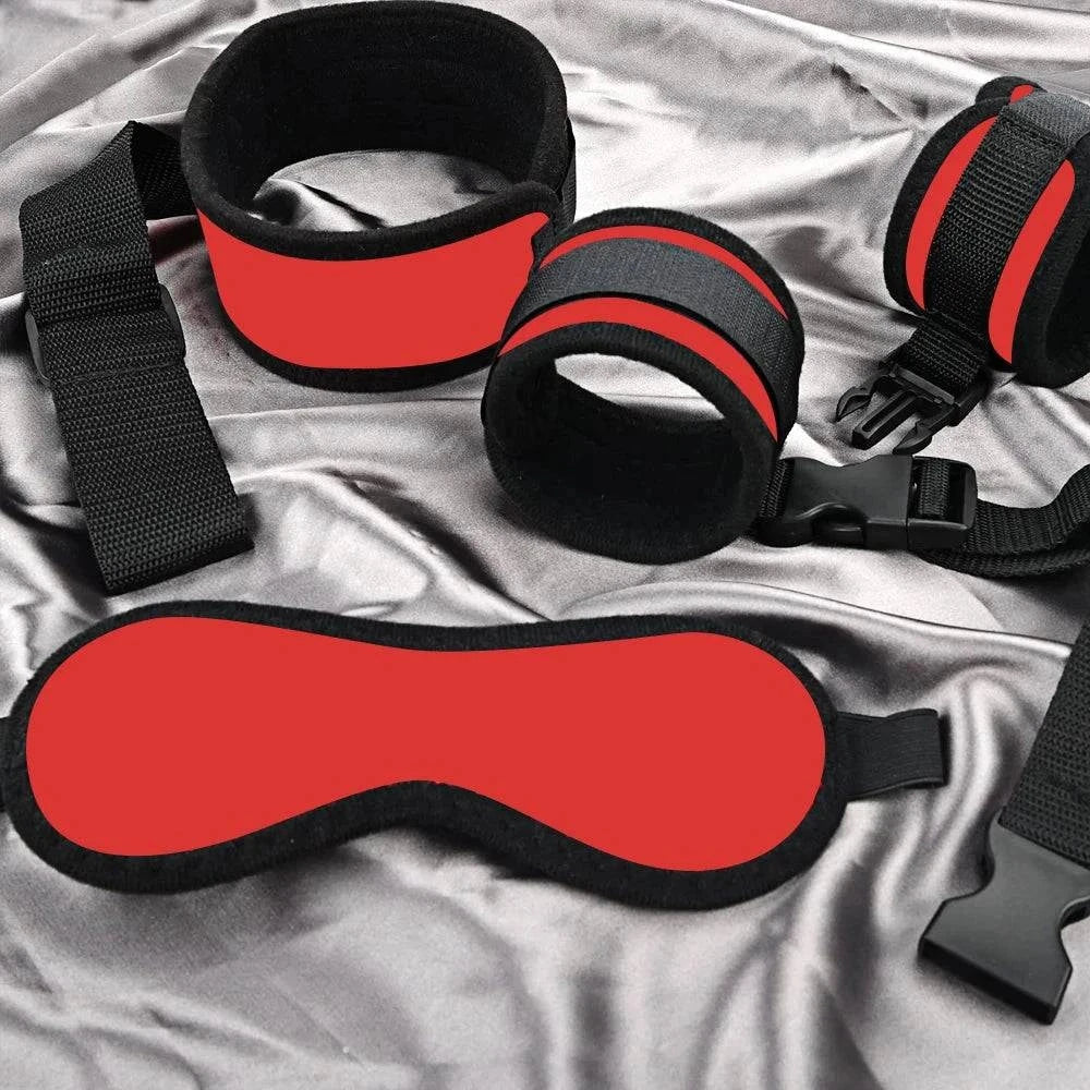 Couples BDSM bondage set with red and black mask, handcuffs, and ankle restraints on satin fabric