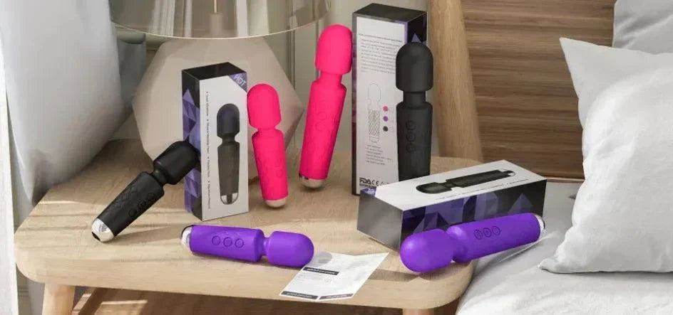 assorted 20-speed powerful AV vibrators in black, pink, and purple on wooden table with packaging and manuals next to a sofa