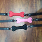 Soft harness mouth silicone dog-bone ball gags in red, pink, and black with adjustable straps on wooden surface
