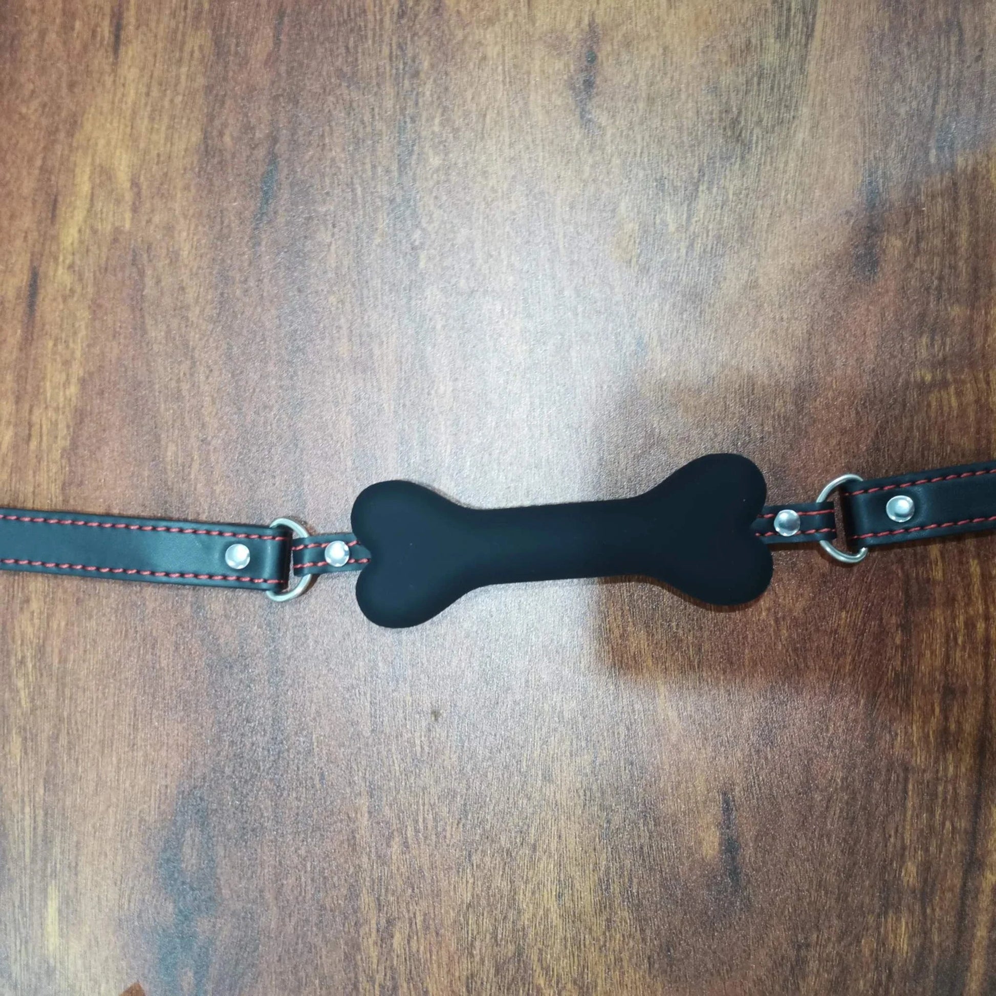 black soft harness mouth silicone dog-bone ball gag with adjustable straps on wooden surface