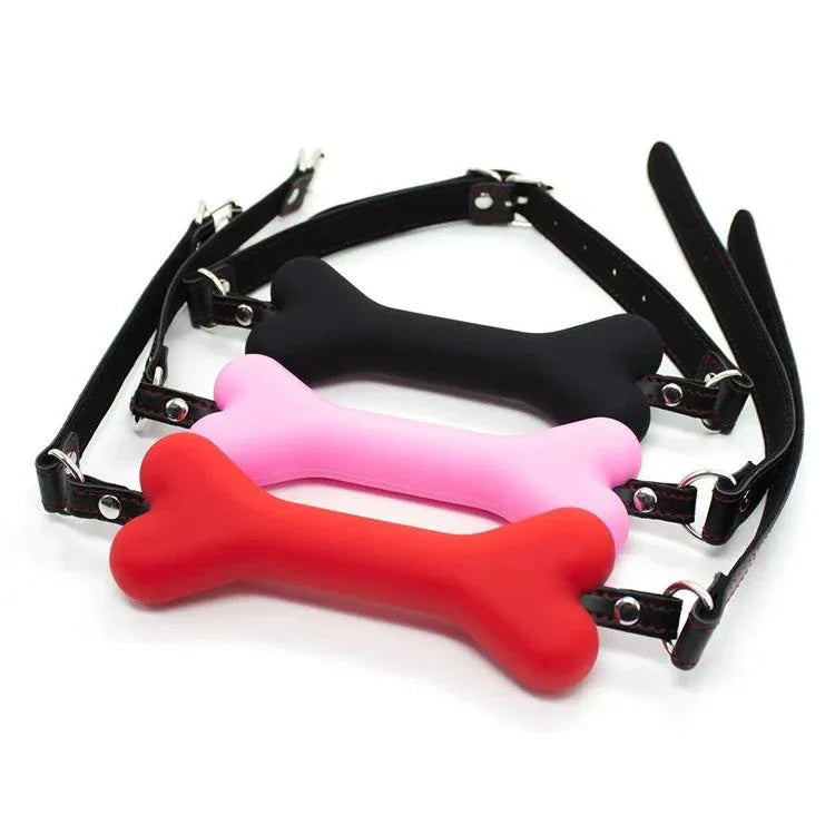 Soft harness mouth dog-bone ball gag in black, pink, and red silicone with adjustable straps for bondage restraint